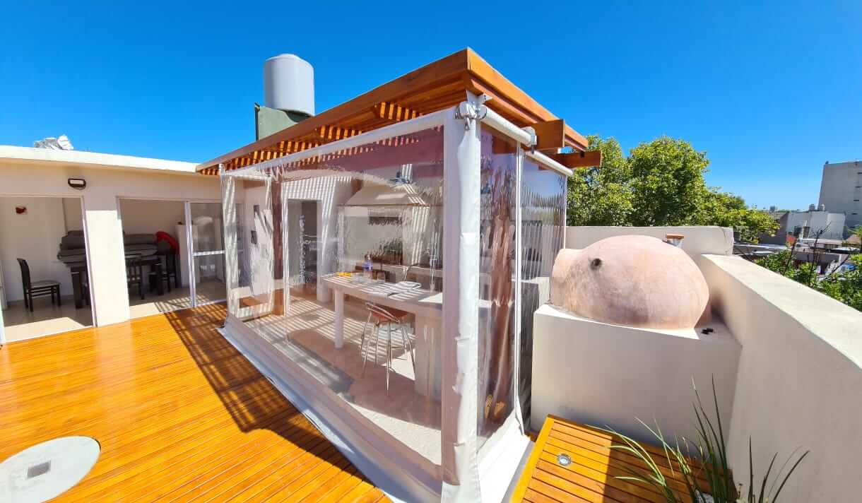 Terraza con deck de madera y parrilla con pergola de madera.