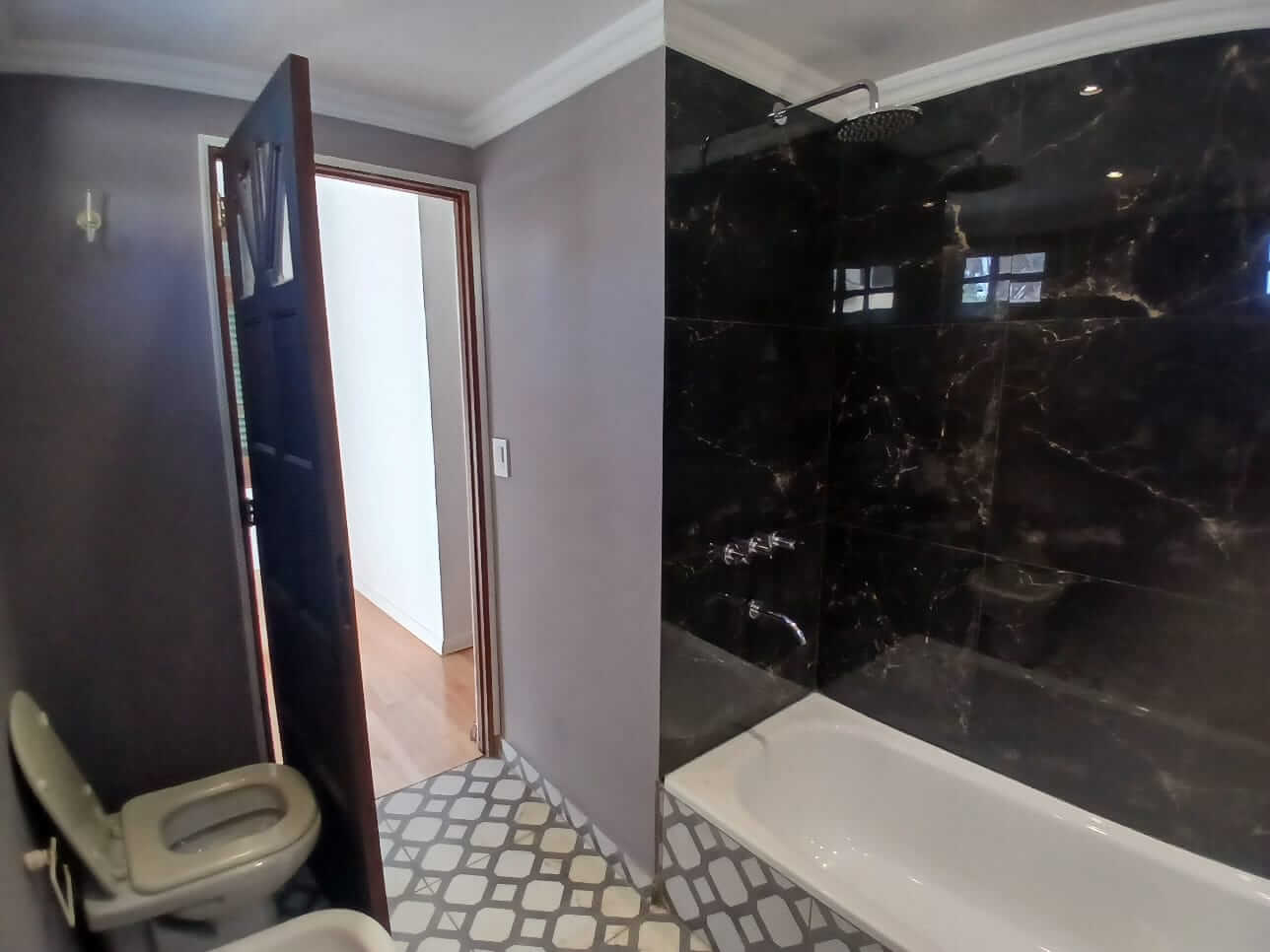 baño con revestimiento tipo marmol negro.